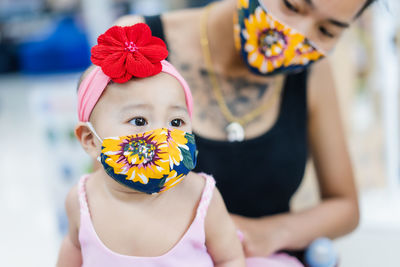 Midsection of mother with cute daughter wearing floral masks