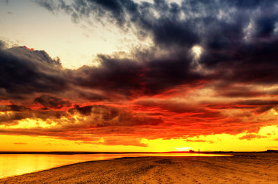 Scenic view of sea against dramatic sky during sunset