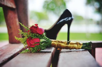 Close-up of red roses with sandal on wooden table