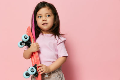 Portrait of cute girl with toy against pink background