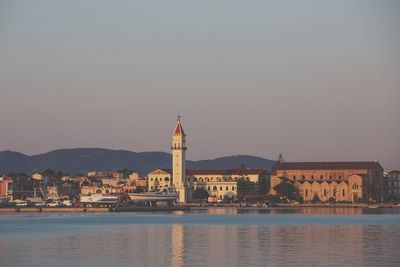 Buildings by river against clear sky