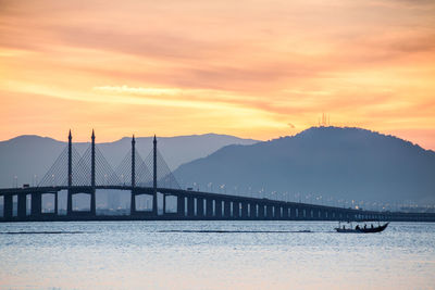 Bridge over water against cloudy sky