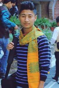 Portrait of young man standing against potted plants