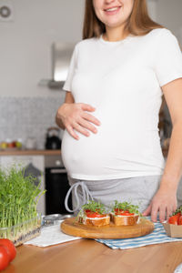 Midsection of woman having food at home