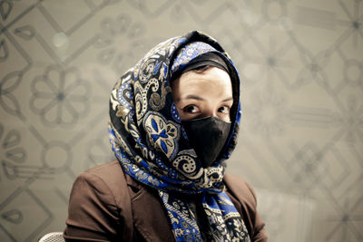 Portrait of woman wearing mask against wall