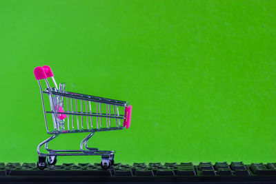 Close-up of figurine shopping cart on keyboard against green background