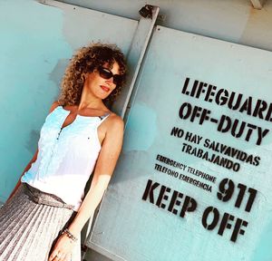 Tilt shot of woman standing by text on metallic wall