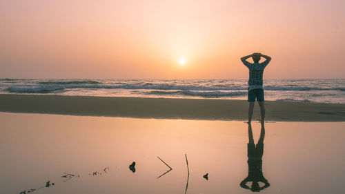 Silhouette person standing on beach against sky during sunset