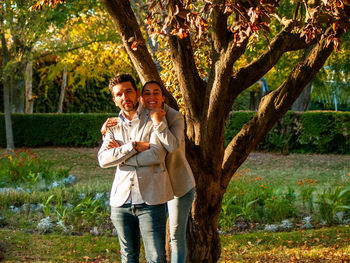 Portrait of smiling couple standing against trees in park