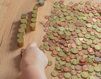 Cropped hand of person holding coins on table