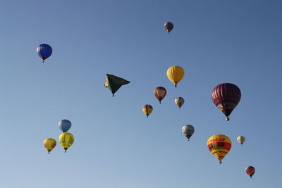 Low angle view of hot air balloons flying against clear sky