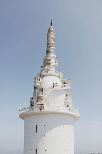 Lighthouse by sea against clear sky