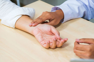 Midsection of couple holding hands on table