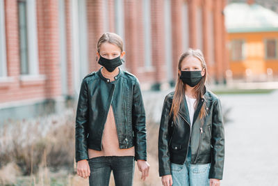 Portrait of girls wearing masks while standing outdoors