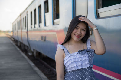 Portrait of smiling young woman standing by train