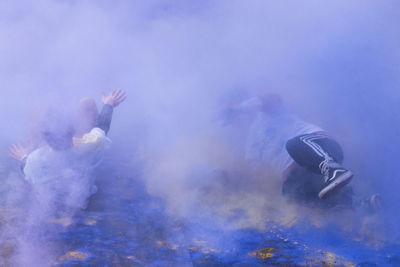 People enjoying amidst purple powder paint during holi