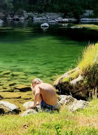 Rear view of boy sitting by lake