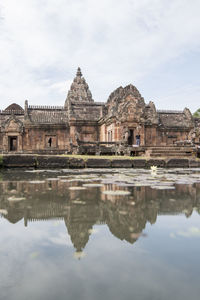 Reflection of old ruins in lake against cloudy sky