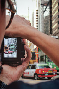 Midsection of man photographing car on city street
