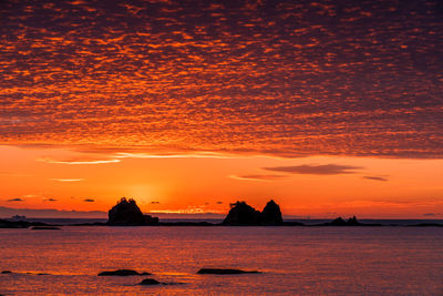 Scenic view of sea against dramatic sky during sunset