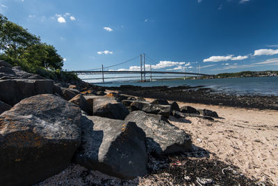 Rocks on bridge over sea against sky