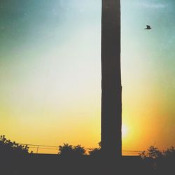 Low angle view of silhouette bird flying against clear sky