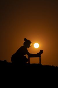 Silhouette man standing on orange against sky during sunset