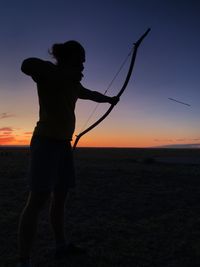 Silhouette man standing on land against sky during sunset