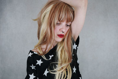 Thoughtful young woman with blond hair against gray background