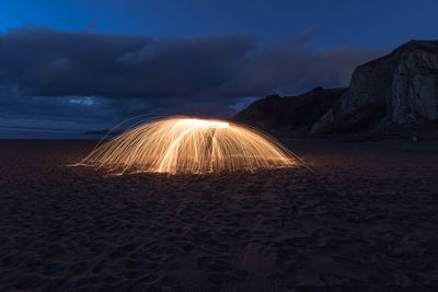 Light trails on beach against sky at night