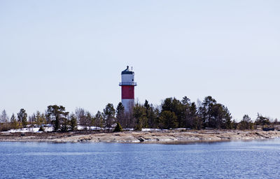 Lighthouse by sea against clear sky