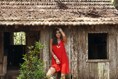 Seducing woman in red dress standing at abandoned house