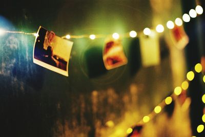 Close-up of photograph hanging from illuminated string lights