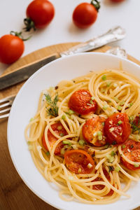 Close up portion of spaghetti pasta with cherry tomatoes sprinkled with spices in a plate