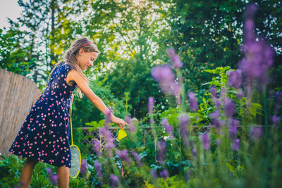 Girl playing badminton while standing by flowering plants