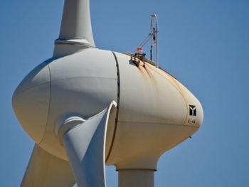 Low angle view of wind turbine against clear blue sky