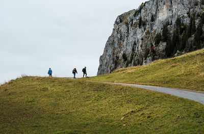 Rear view of people walking on mountain against sky