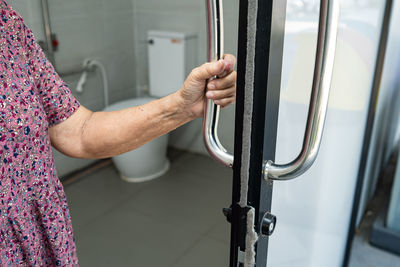 Midsection of senior woman holding door