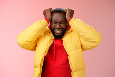 Portrait of young man standing against red background