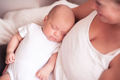 Mother holding sleeping baby at home