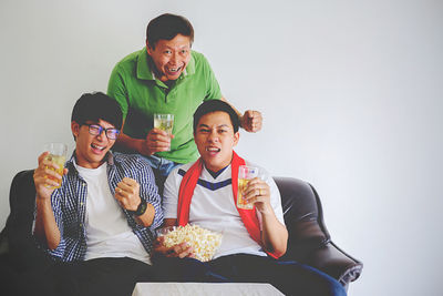 Cheerful men having beer while watching tv at home