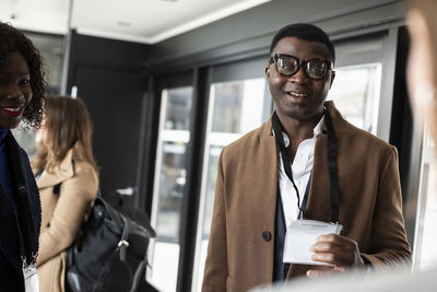 Businessman with eyeglasses showing id card to receptionist at conference center