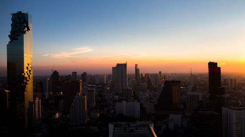 Modern buildings in city against sky during sunset