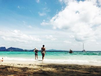 Friends standing on beach against sky