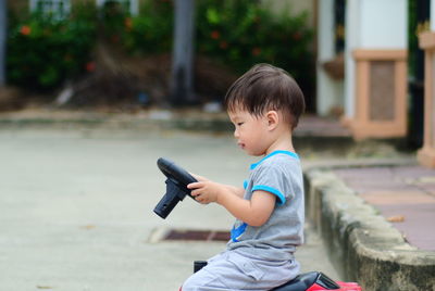 Side view of boy on toy car on footpath