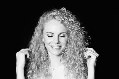 Portrait of young woman against black background