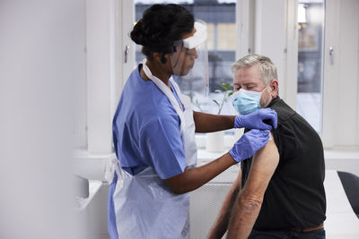 Female doctor vaccinating senior patient