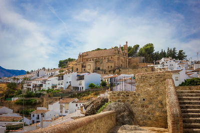 Buildings in town against cloudy sky