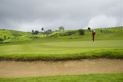 Man standing on golf course against sky