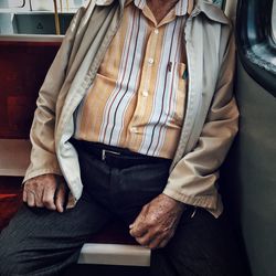 Midsection of man sitting in train